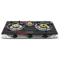 A three-burner gas stove with a glossy black glass front, accented with red graphic lines and gold burner caps. The brand name 'implex' is printed in white on the front.