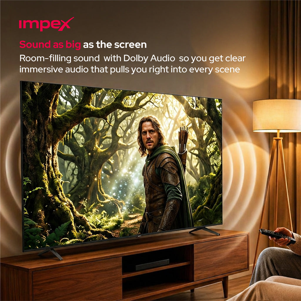 A large flat-screen TV on a wooden console in a living room, displaying a forest scene with a warrior character. The room has warm lighting from a floor lamp, and a hand holding a remote is visible in the lower right.